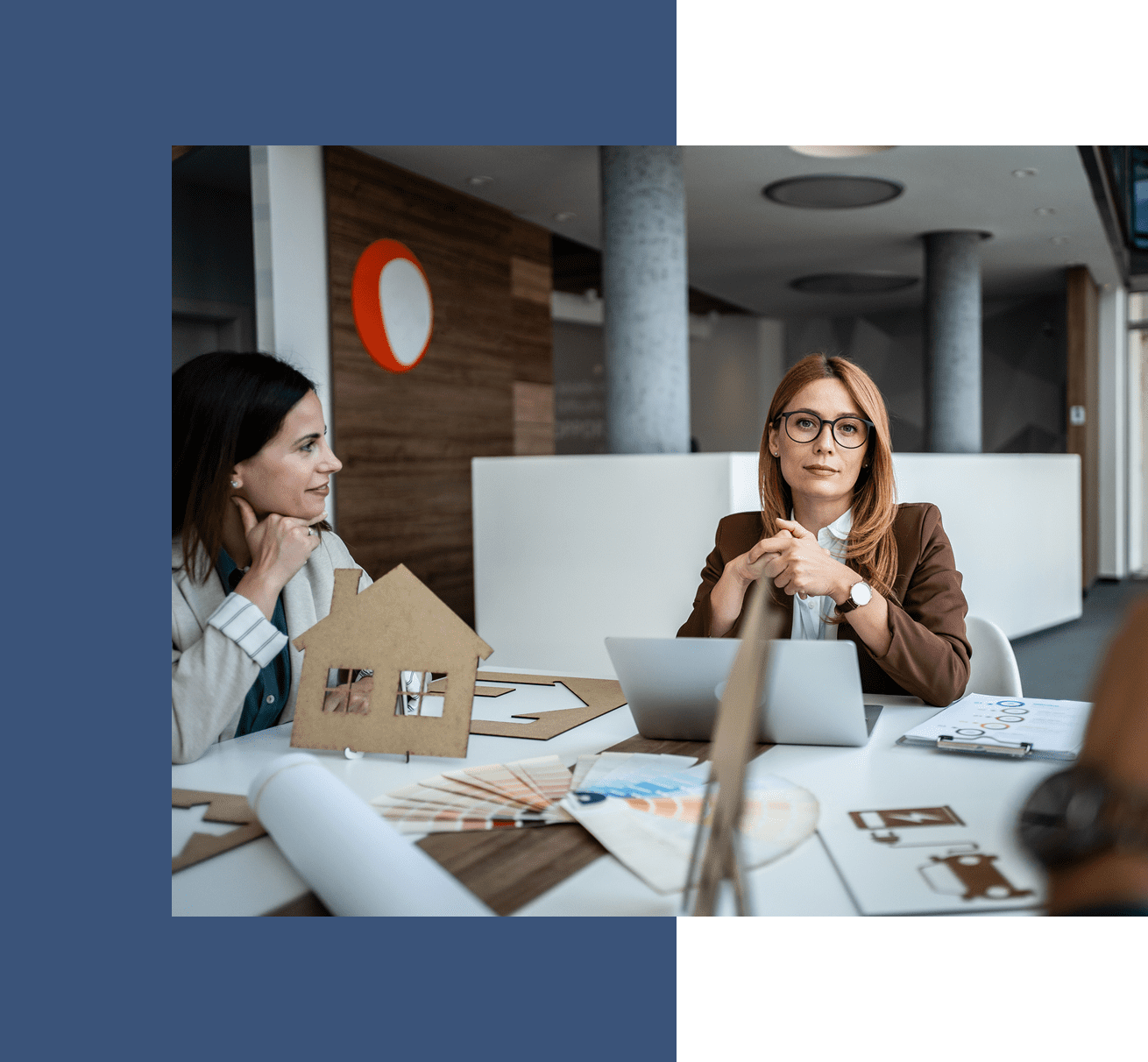 Women discussing architectural plans at table.