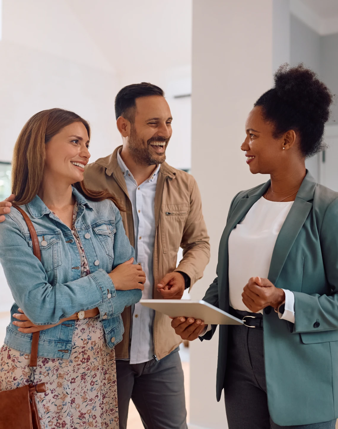 Three people smiling and talking indoors.