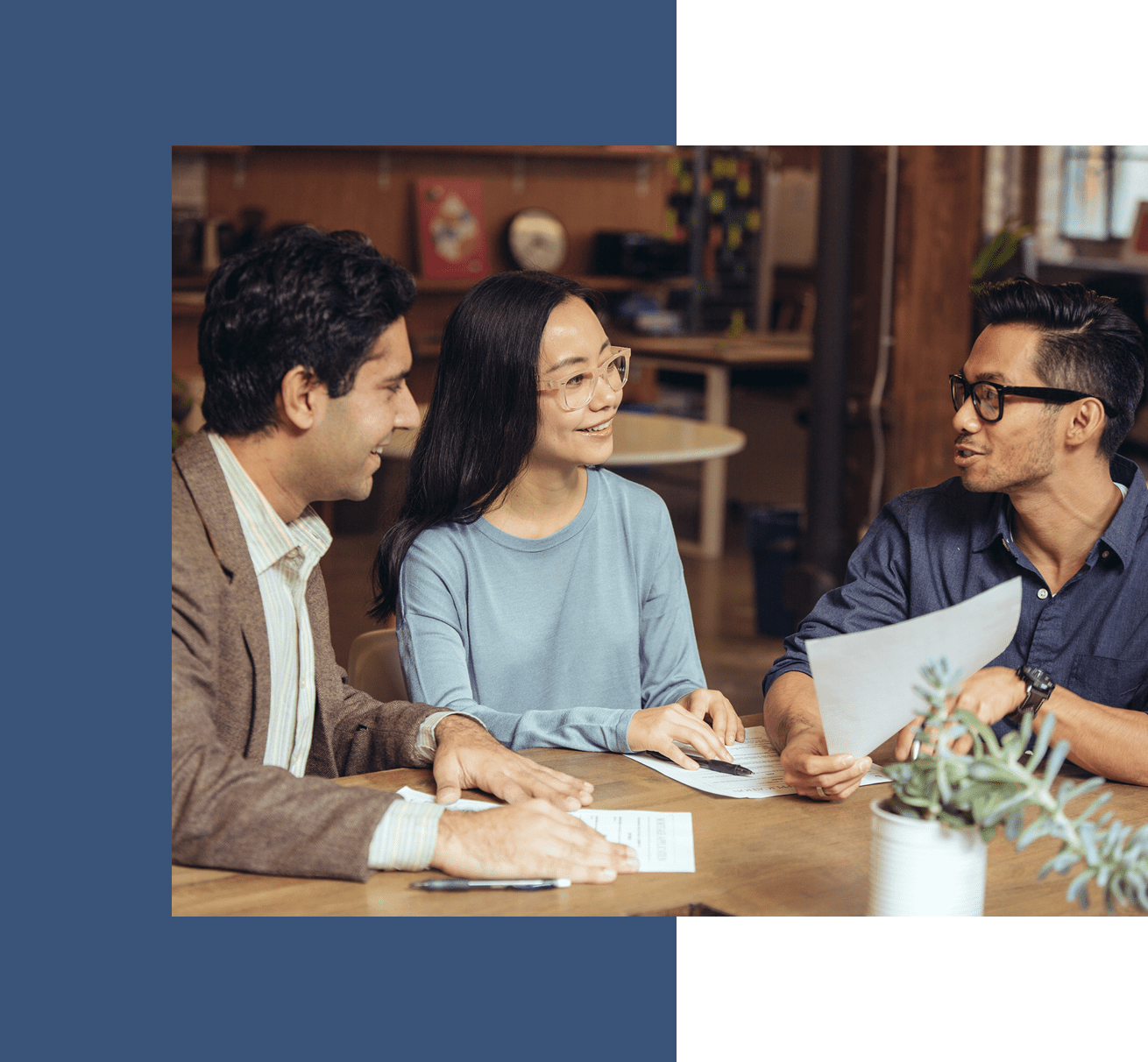 Three people discussing documents at table.